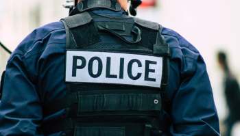 A close-up of a police officer's back, featuring a prominently displayed "POLICE" label on their uniform.