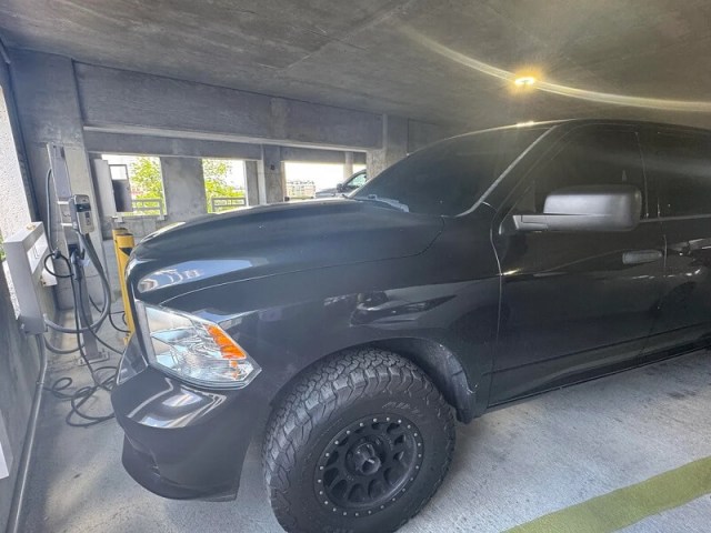 A black pickup truck parked in a concrete garage with visible rugged tires.