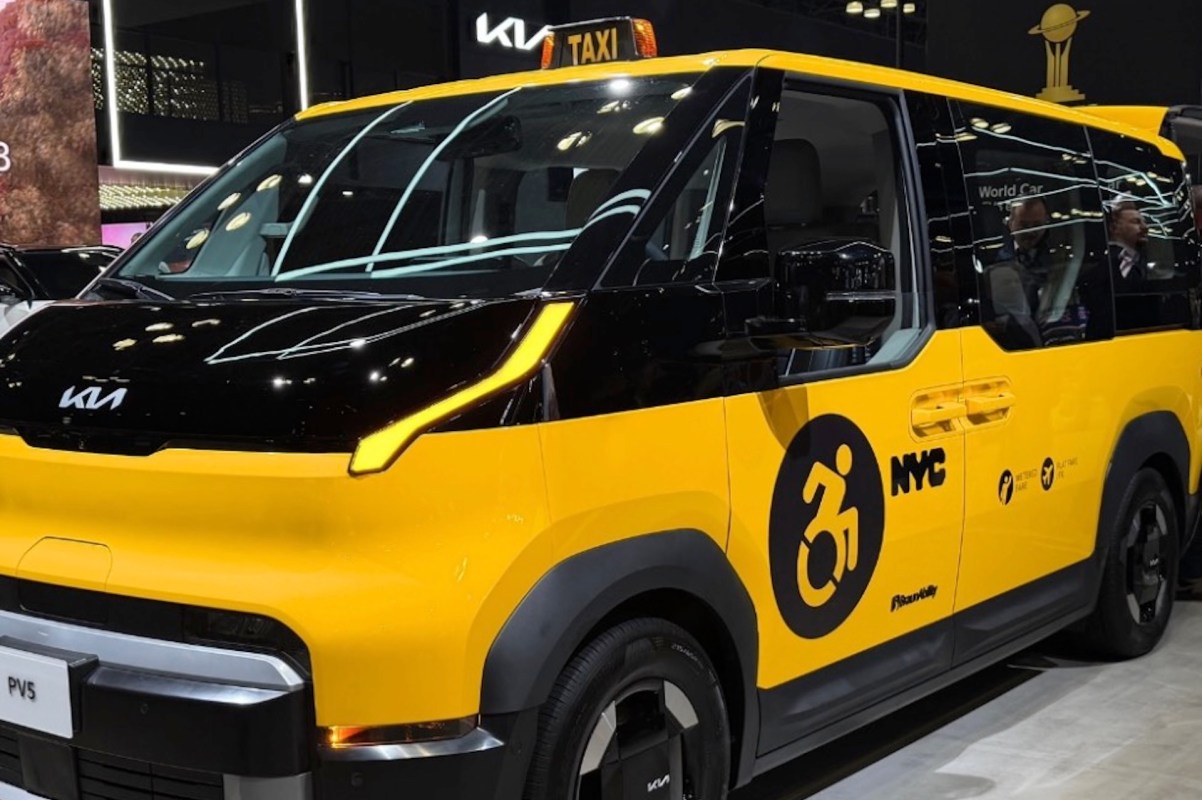 A yellow and black Kia taxi designed for accessibility, featuring a wheelchair symbol and NYC markings.