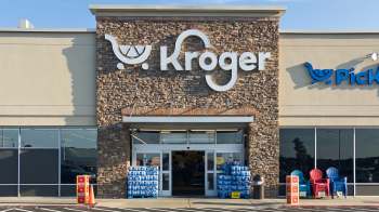 A grocery store exterior featuring the Kroger logo, entryway, and stacked water bottles.