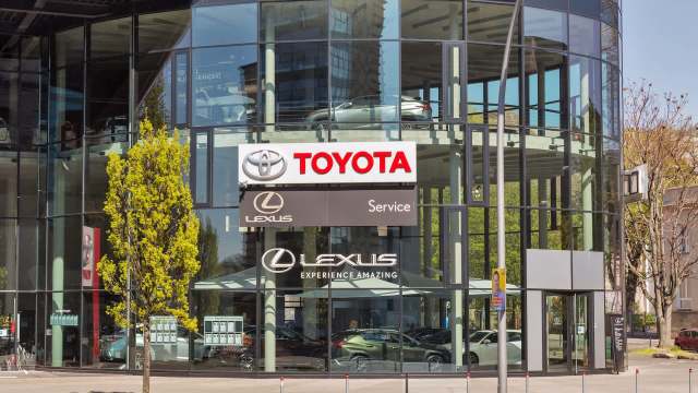 A modern car dealership showcasing Toyota and Lexus signage with large glass windows and a landscaped entrance.
