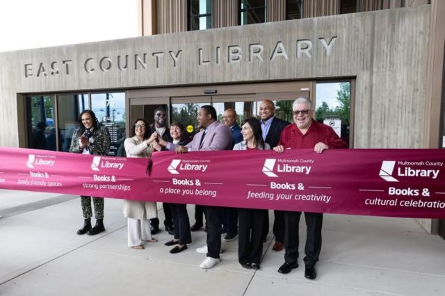 People celebrating the library's opening with a ribbon cutting.
