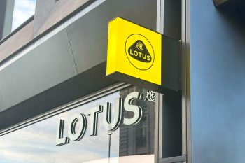A bright yellow sign with the word "LOTUS" hangs over a storefront window displaying the same name.