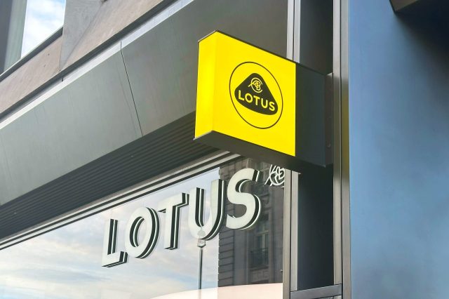A bright yellow sign with the word "LOTUS" hangs over a storefront window displaying the same name.