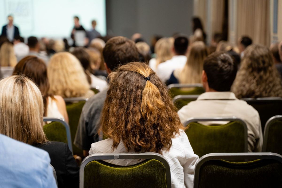A crowd of people seated in a conference room, focusing on a presentation at the front.
