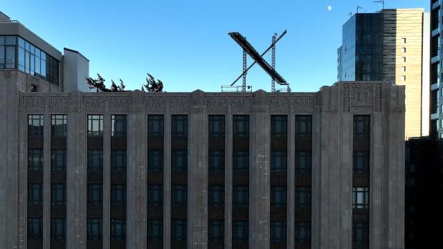 A historic building with intricate detailing, featuring a large X-shaped structure on its rooftop against a clear sky.