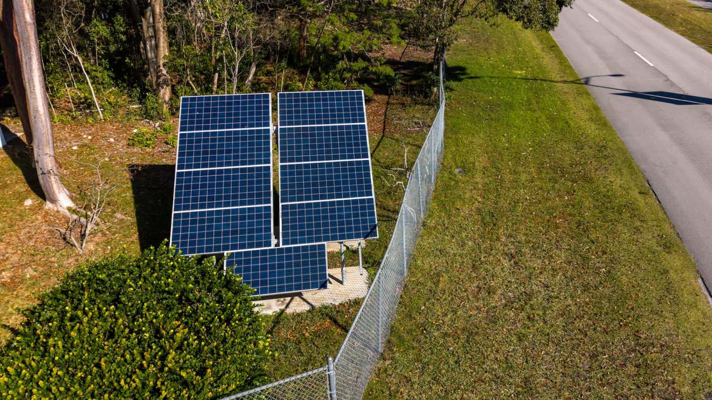 A fenced solar panel installation near a road.