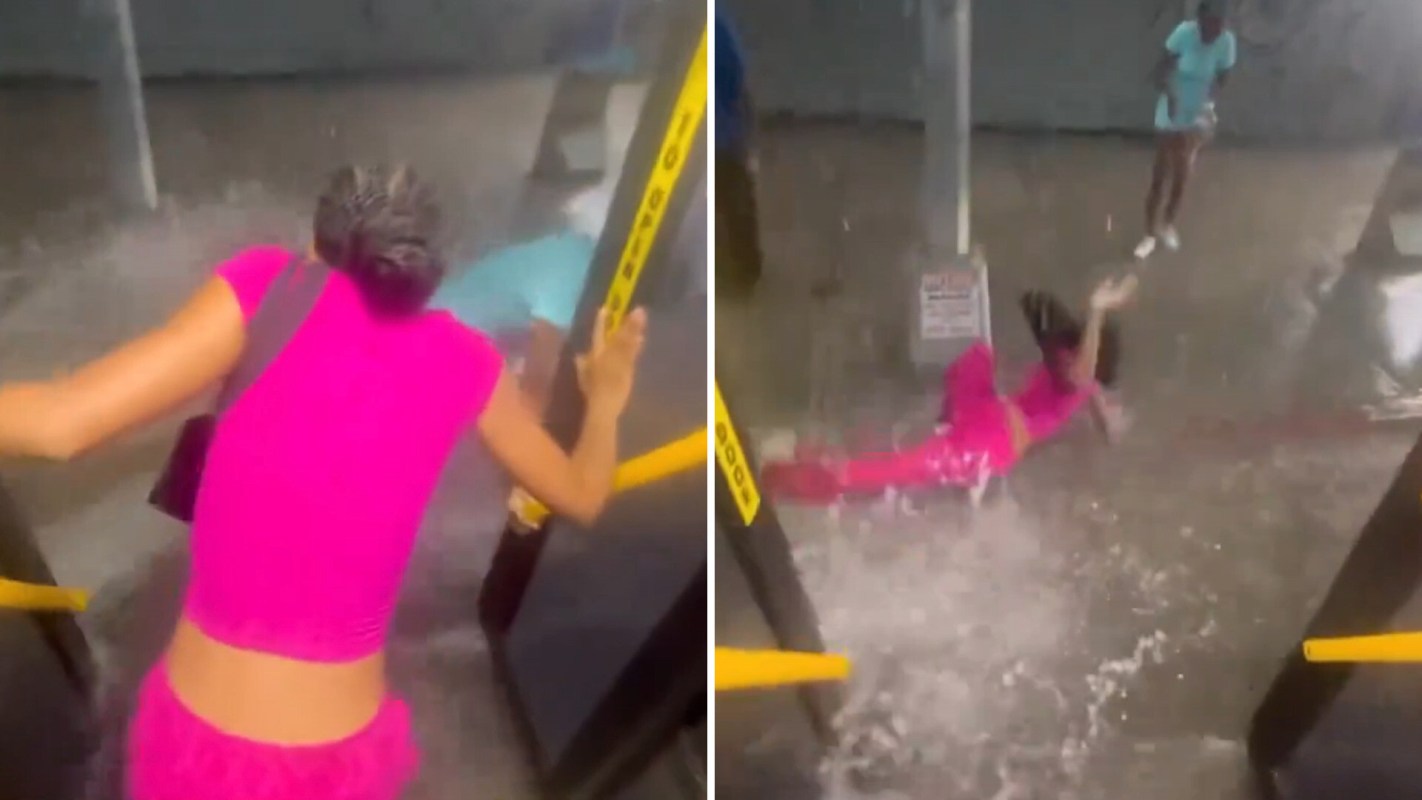 A woman in bright pink clothing slips and falls into a flooded area.