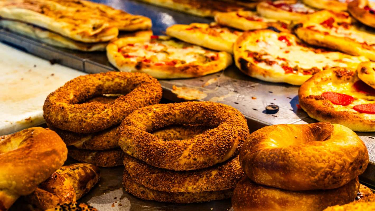 A display of various bagels and flatbread pizzas, topped with cheese and pepperoni.