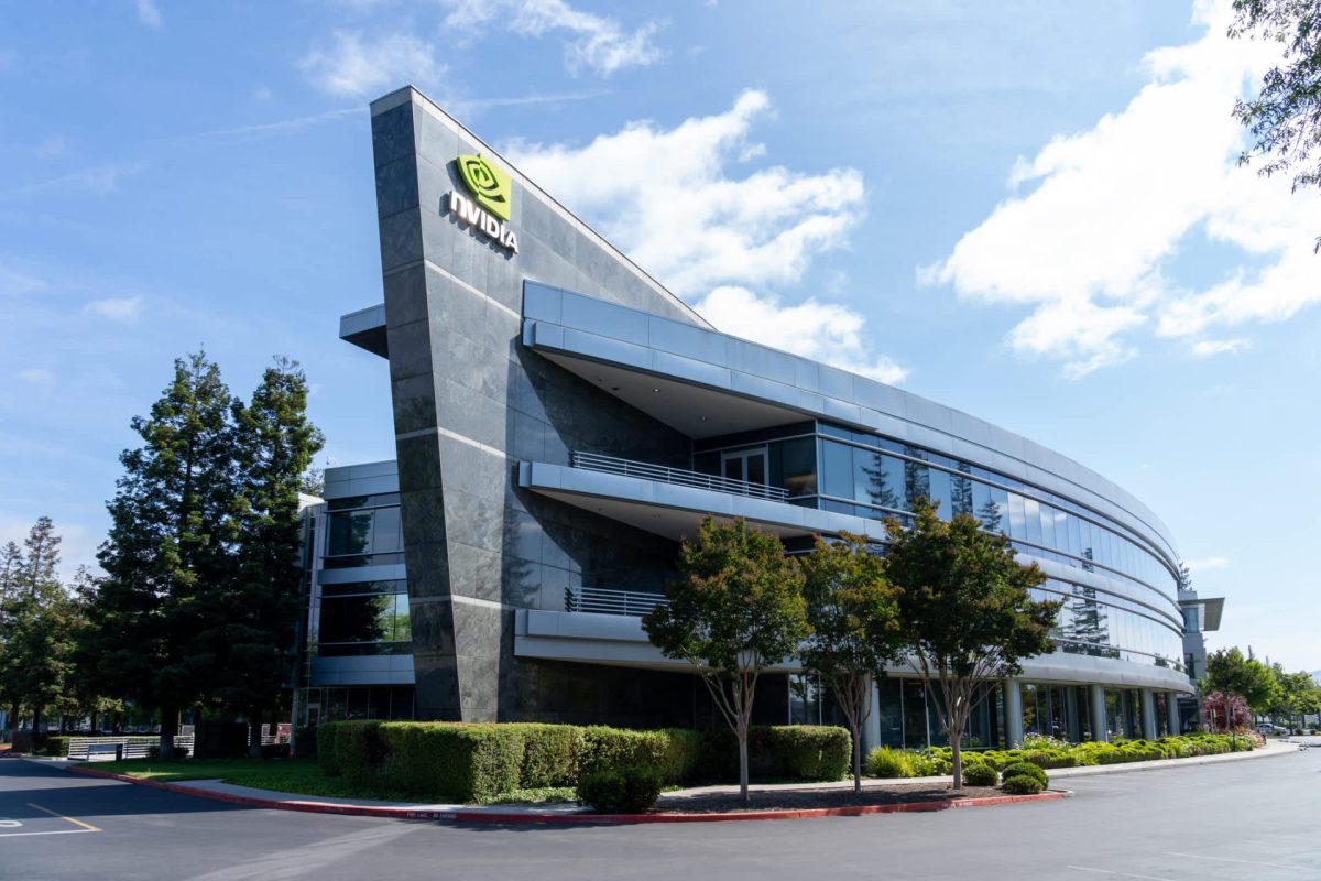 A modern building with large glass windows and an NVIDIA logo, surrounded by greenery and blue skies.
