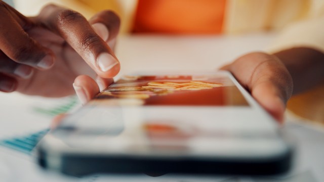 A close-up of a hand interacting with a smartphone displaying a colorful food image.