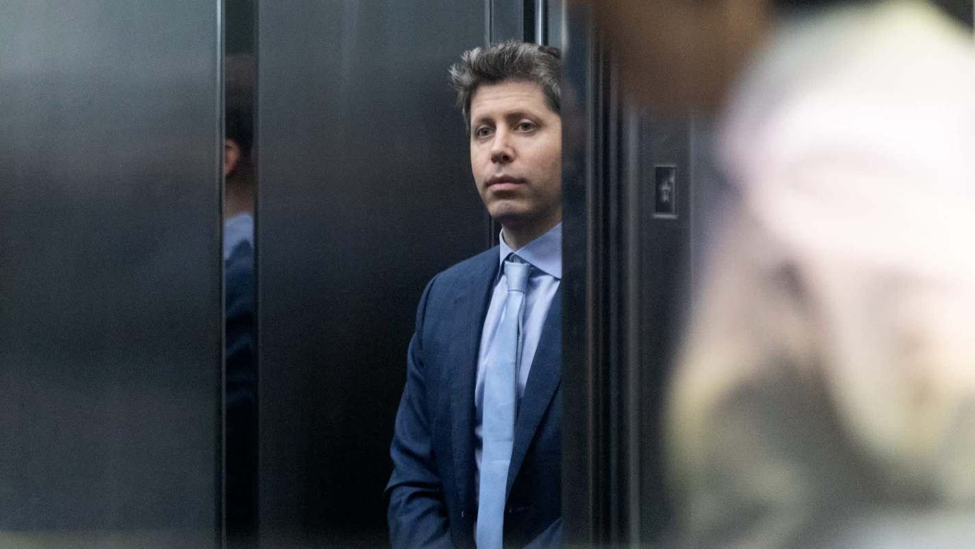 A man in a business suit stands quietly in an elevator, reflecting a serious expression.