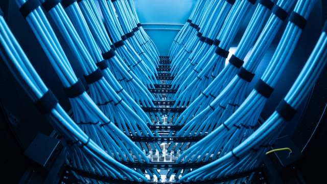 Blue network cables inside a server rack illuminated by cool lighting.