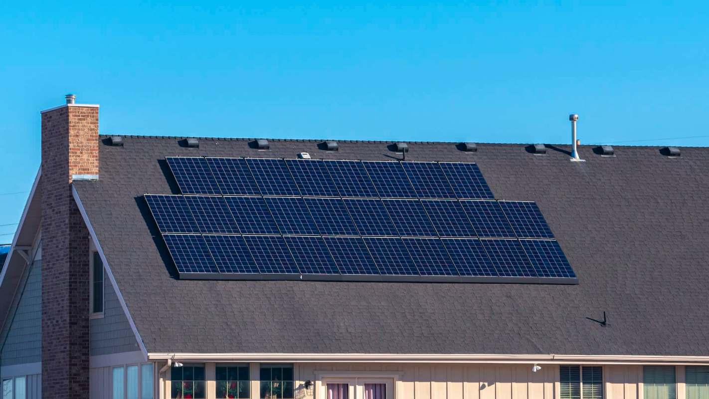 A house with solar panels on its sloped roof on a clear day.