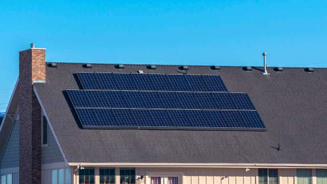 A house with solar panels on its sloped roof on a clear day.