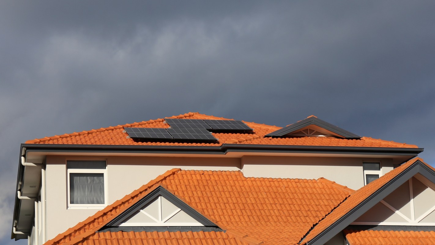 A house with an orange tiled roof featuring solar panels.