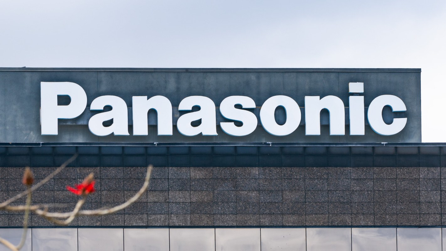 A close-up view of the Panasonic logo on a modern building against a cloudy sky.