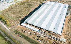 An aerial view of a large commercial building under construction, surrounded by machinery and vehicles.