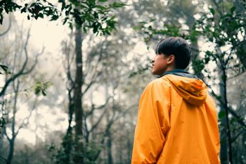 A person hiking while wearing a yellow rain jacket.
