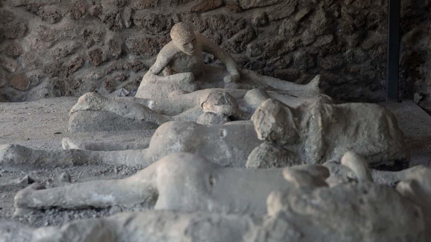 Plaster casts of figures lying on the ground, depicting victims from the Pompeii eruption.