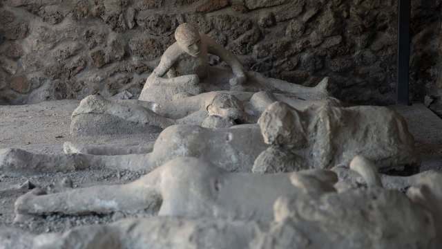 Plaster casts of figures lying on the ground, depicting victims from the Pompeii eruption.
