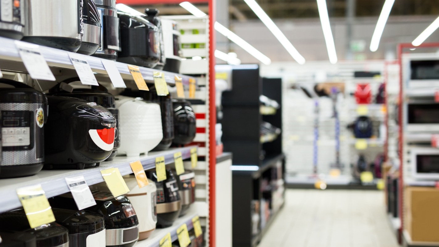 A view of a retail store aisle displaying various pressure cookers and kitchen appliances on the shelves.