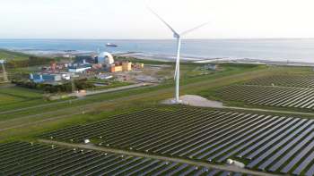 Solar panels with a wind turbine and a nuclear power plant near a coast.