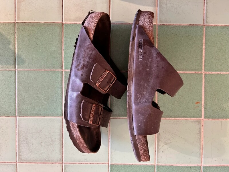 A worn pair of Birkenstock sandals with leather straps.
