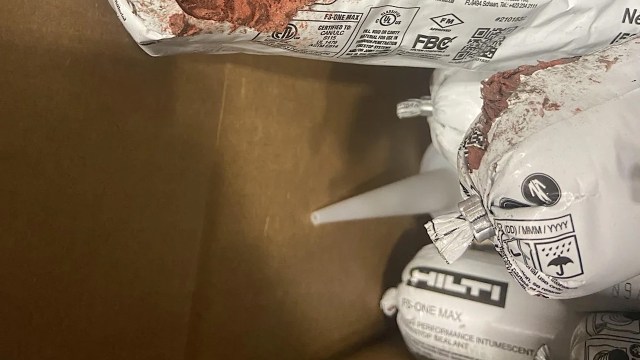 Several sealed bags of Hilti construction materials are partially visible inside a brown cardboard box.