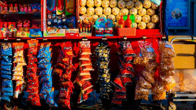 A colorful snack stand displaying various chips, candies, and popcorn in brightly labeled bags.