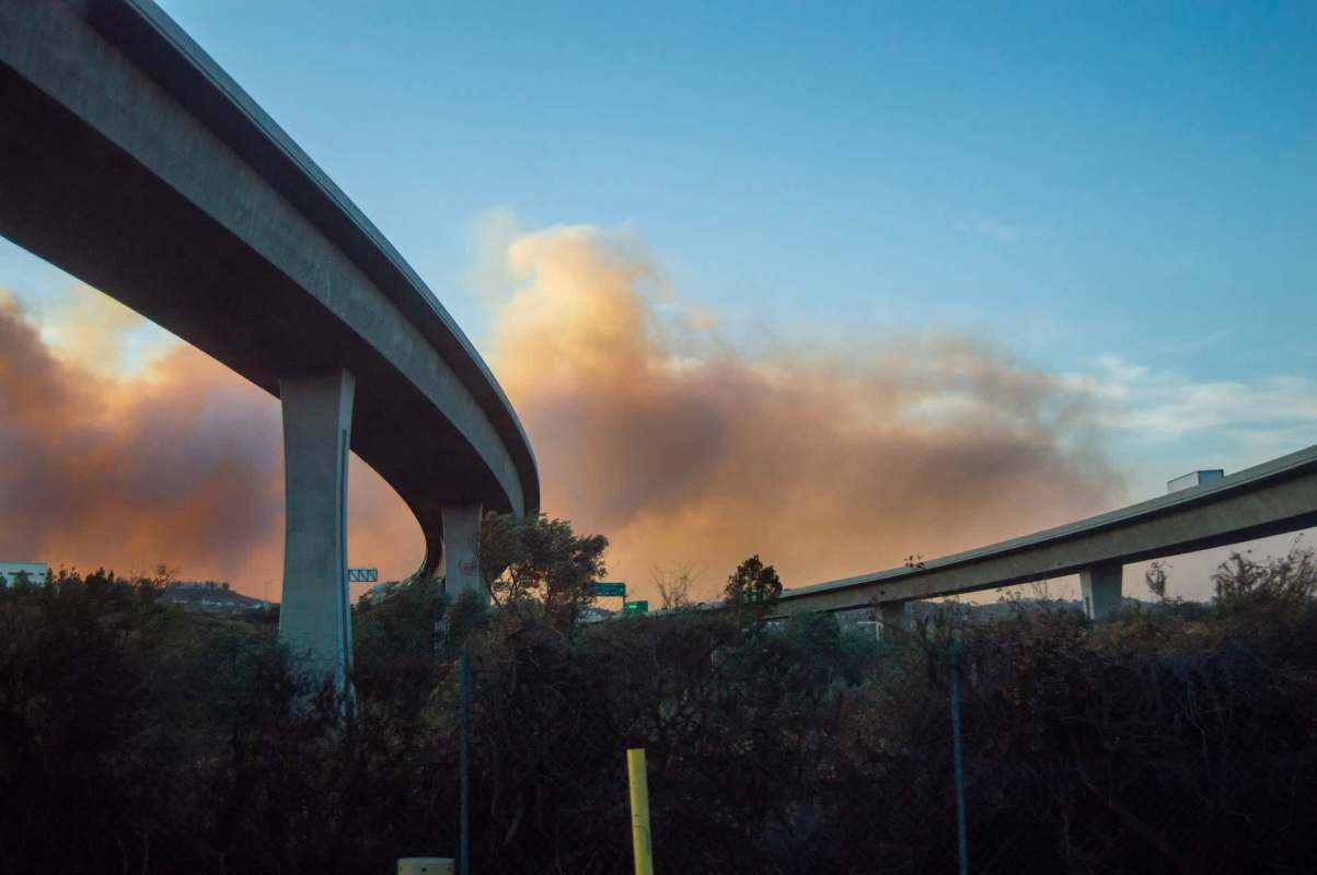 Two elevated highways at sunset with wildfire smoke in the distance.
