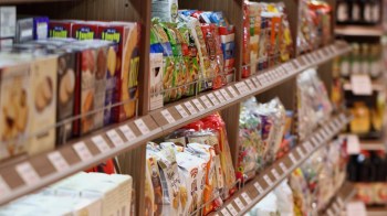 A grocery store aisle filled with various packaged snacks and food products on neatly arranged shelves.