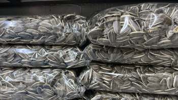 Several packages of sunflower seeds stacked in a dark storage space.