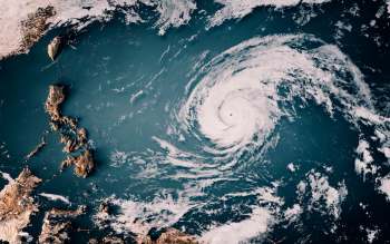 Aerial view of a large hurricane swirling over the Pacific Ocean near a group of islands.