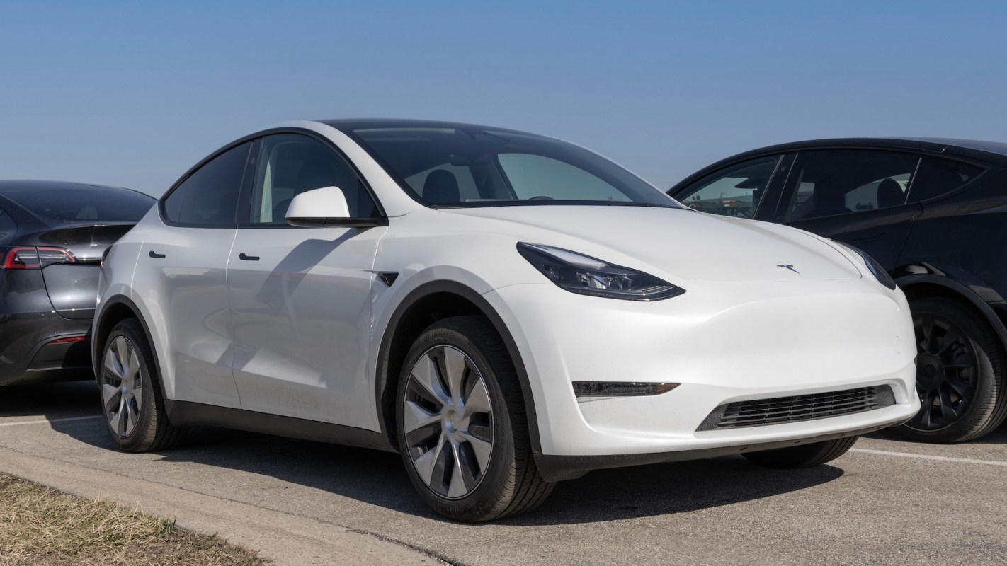 A white Tesla Model Y parked next to two darker vehicles.