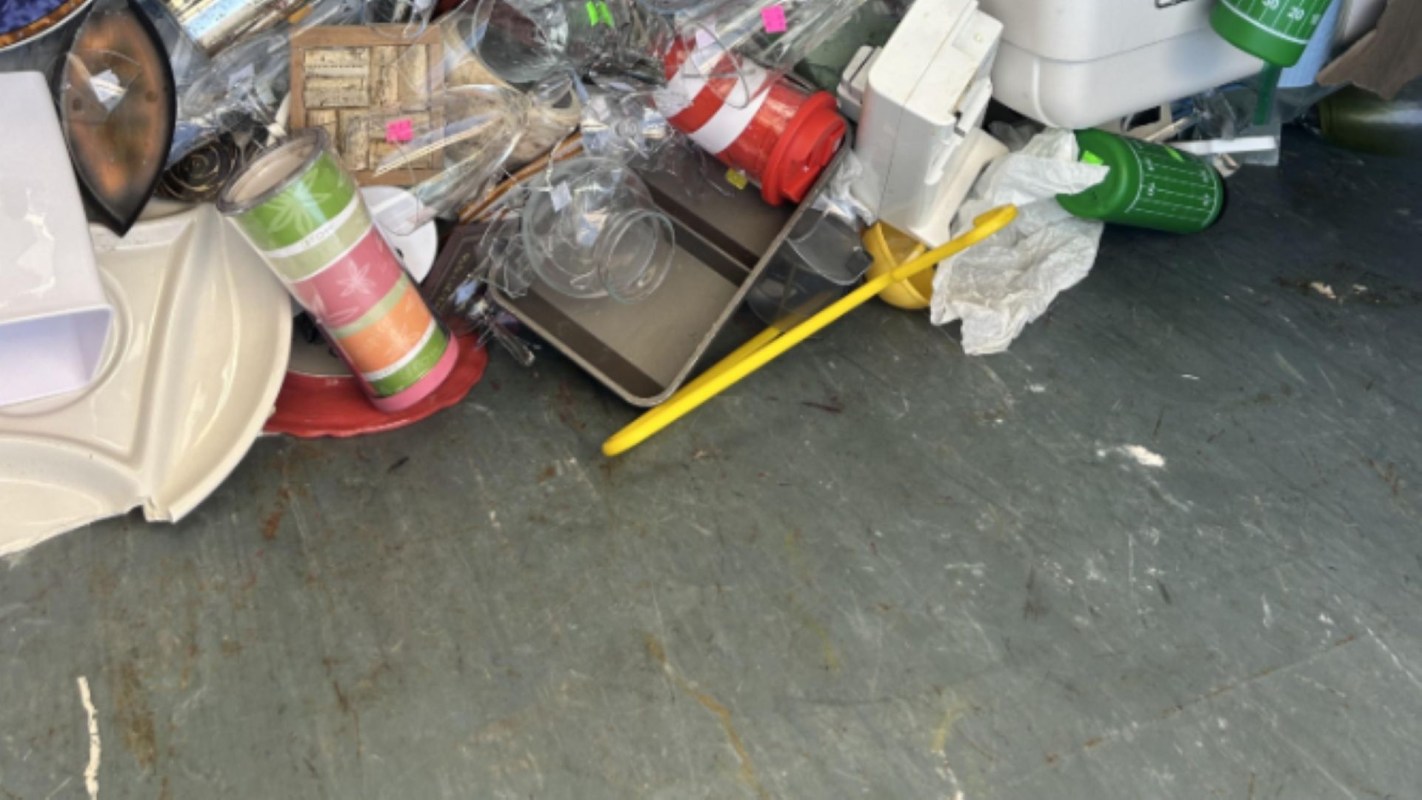 A pile of assorted discarded items including plastic cups, containers, and pieces of packaging on a floor.