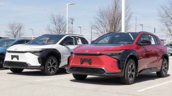 Two new Toyota bZ4 SUVs, one white with black accents and one red, parked in a dealership lot.