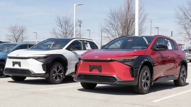 Two new Toyota bZ4 SUVs, one white with black accents and one red, parked in a dealership lot.