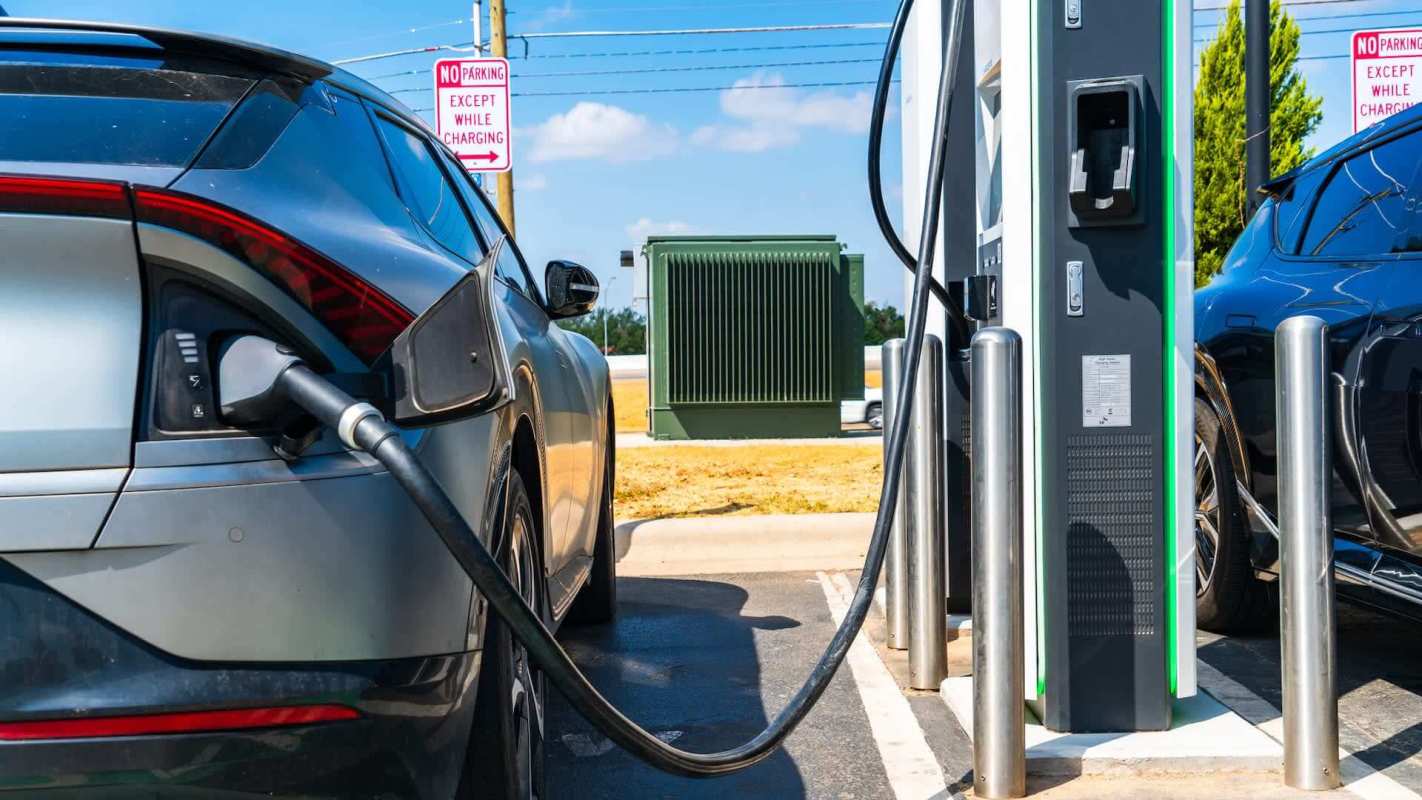 An electric vehicle charging at a station with a sign that reads, "No Parking Except While Charging."