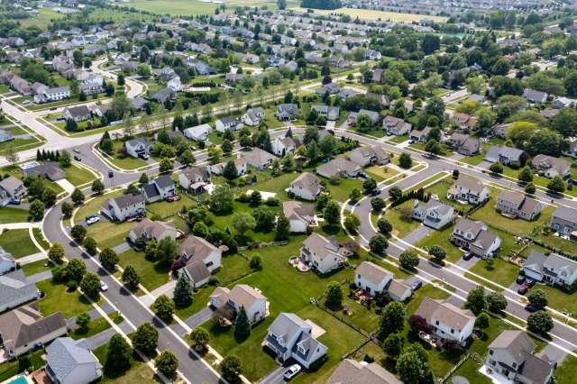 Aerial view of a suburban neighborhood featuring winding streets and houses with yards.