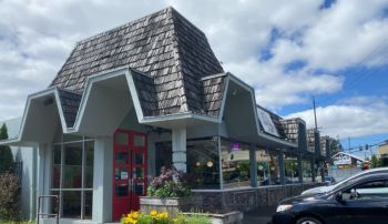 A building with a peaked, shingled roof and red double doors.
