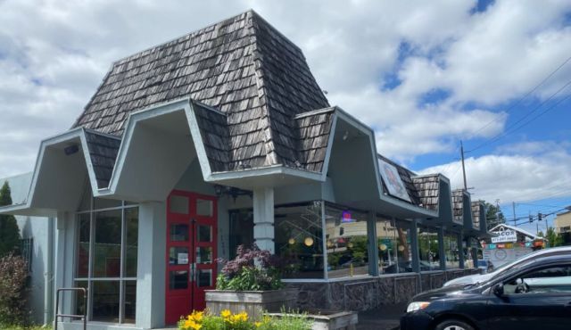 A building with a peaked, shingled roof and red double doors.