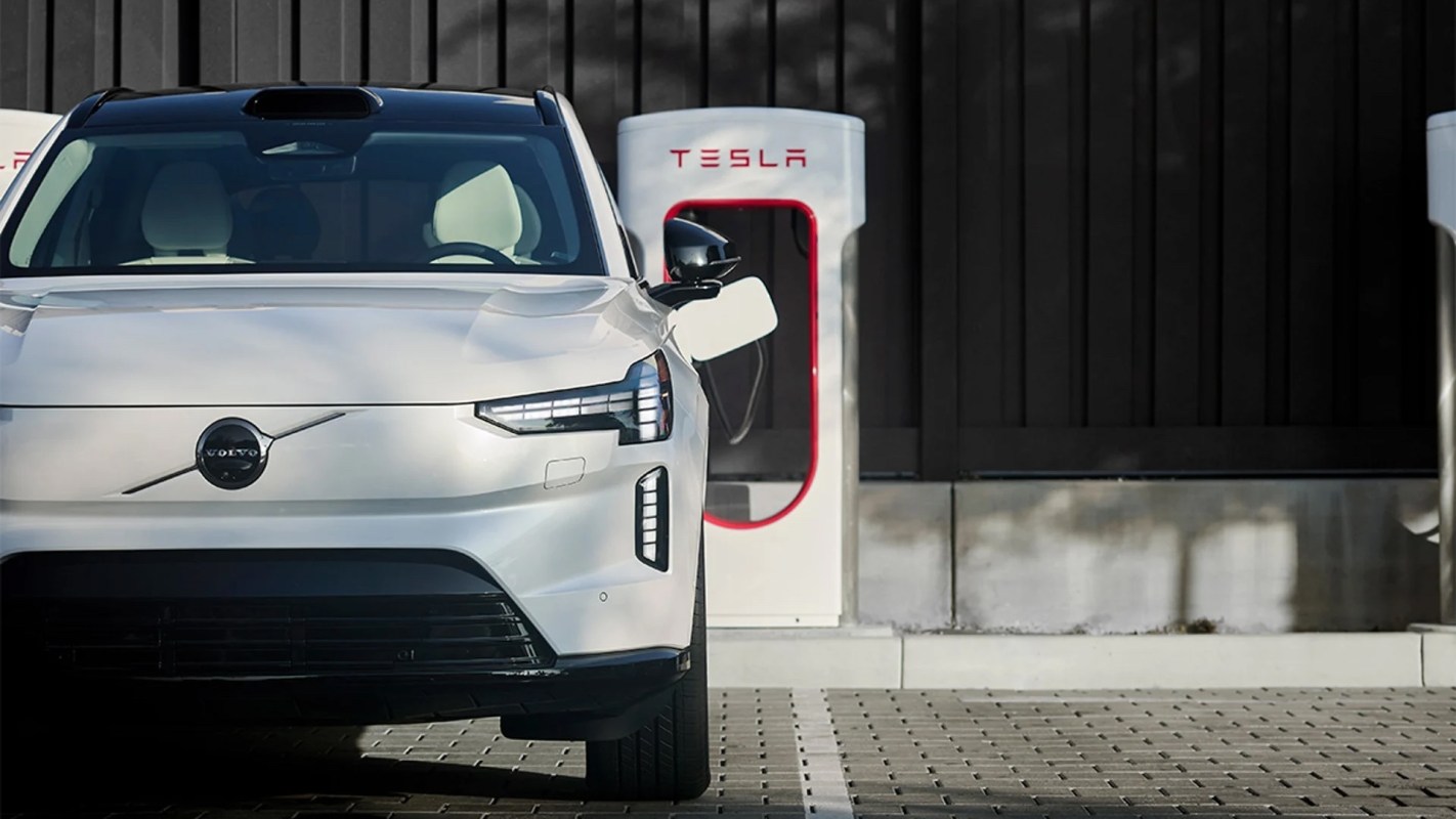 A silver Volvo EV at a Tesla charging station.