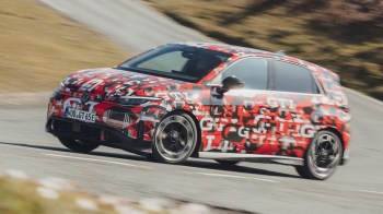 A Volkswagen car with a vibrant camouflage wrap is speeding around a winding road.