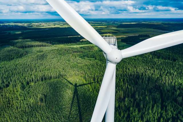 Aerial view of a wind turbine overlooking a forest.