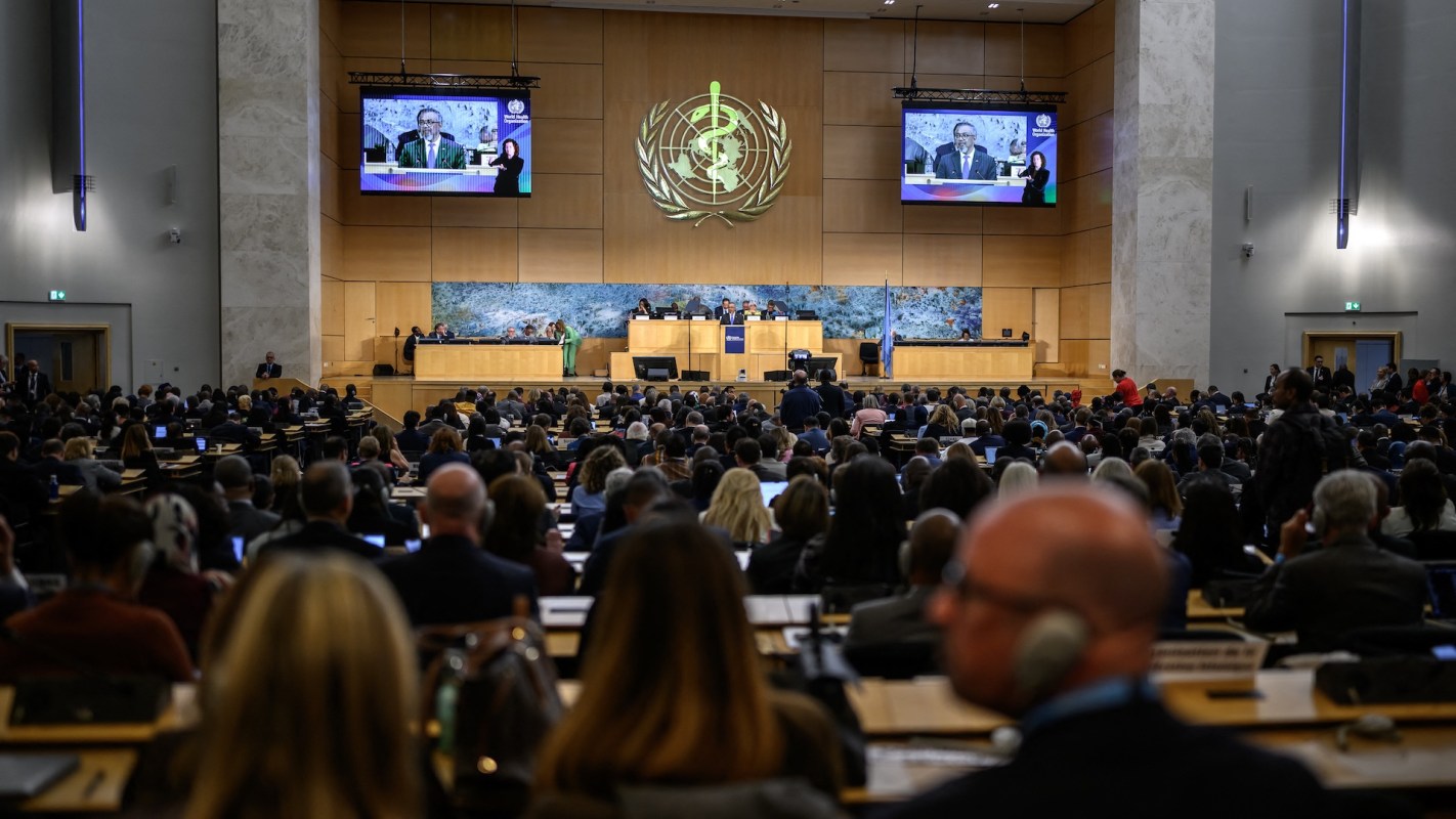 A large audience listens to a speaker on stage.