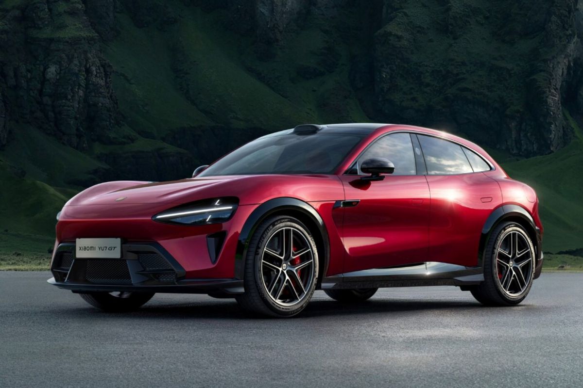 A sleek red SUV with modern design parked against a backdrop of green mountains.