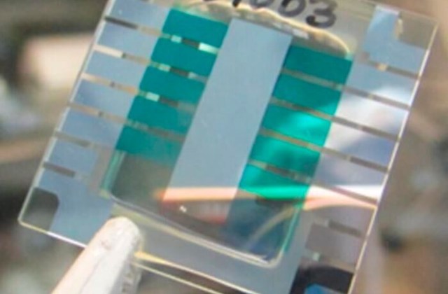 A clear glass slide with a patterned surface featuring alternating stripes of light and dark blue-green materials.