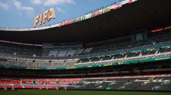 A panoramic view of a partially empty stadium featuring FIFA World Cup 2026 signage and multiple country flags.