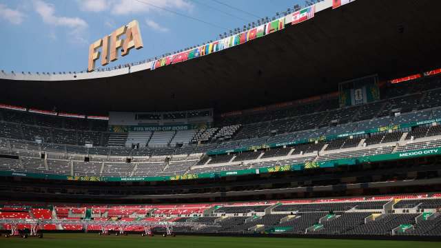 A panoramic view of a partially empty stadium featuring FIFA World Cup 2026 signage and multiple country flags.